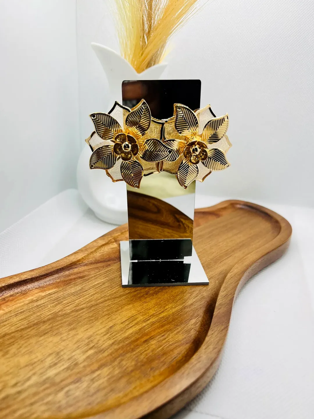 Floral gold earrings arranged on a wooden tray